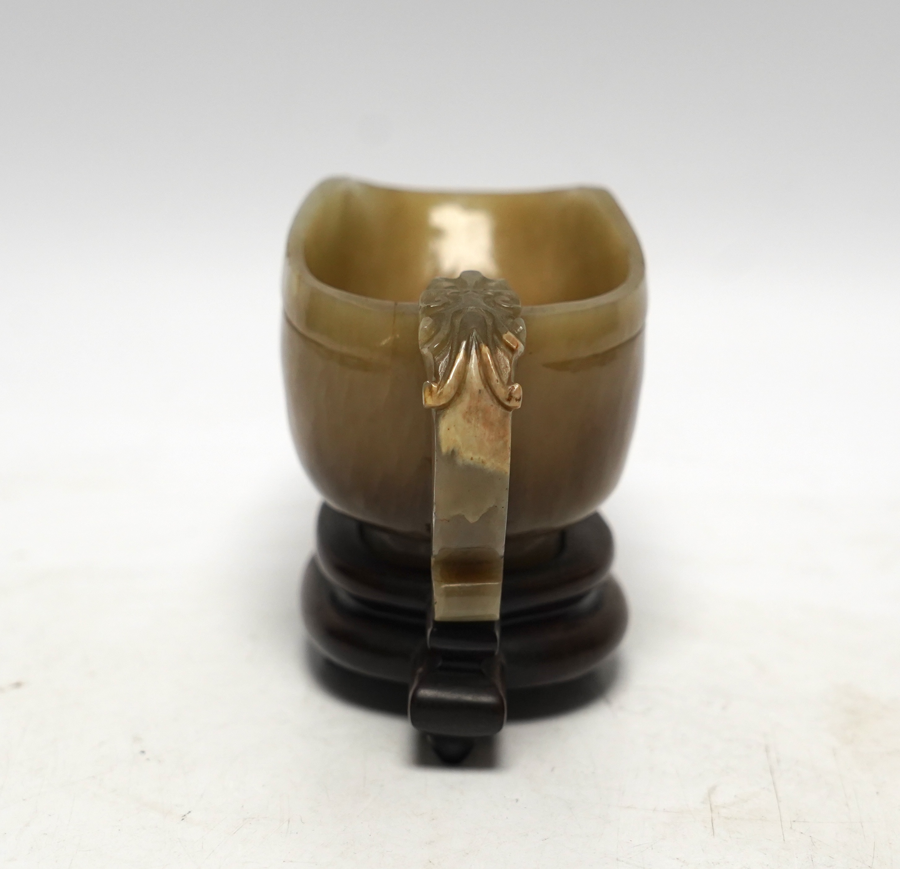 An 18th century Chinese archaistic jade pouring vessel, yi, with carved dragon handle, 6cm high, on a hardwood stand